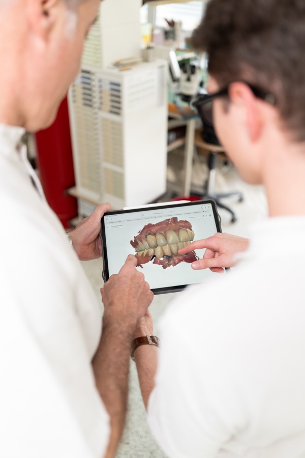 Zwei Zahntechniker besprechen einen Intraoralscan am Tablet
