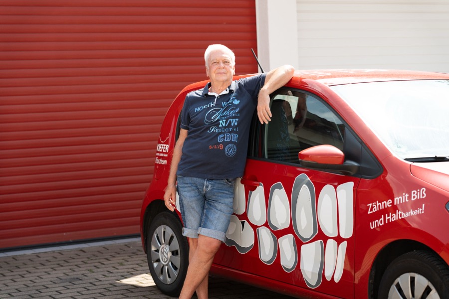 Fahrer des Dentallabors Kiefer am roten Laborfahrzeug