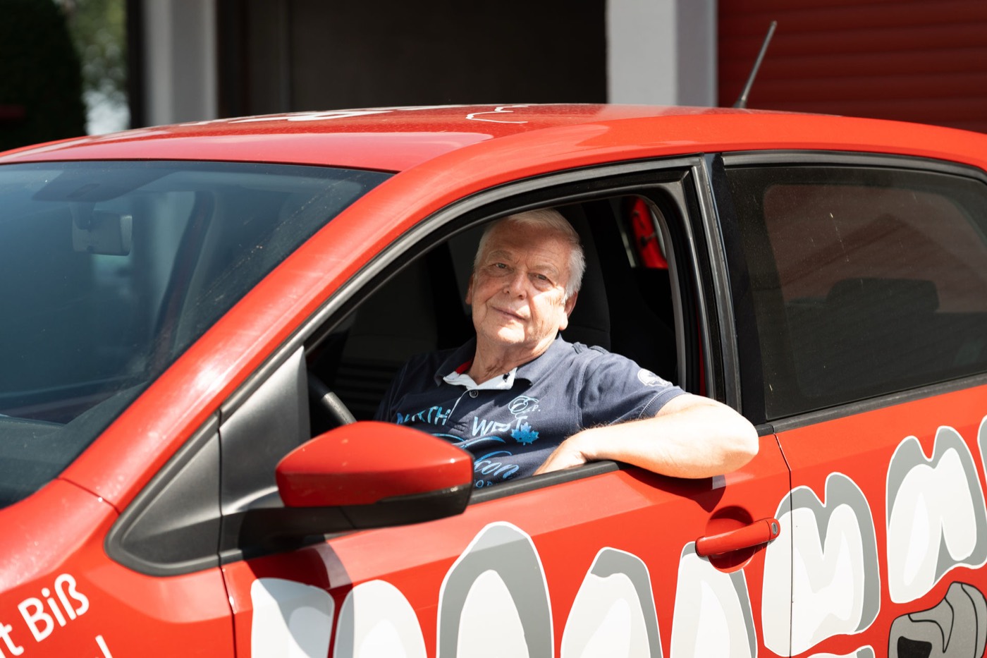 Fahrer des Dentallabors Kiefer im roten Laborfahrzeug