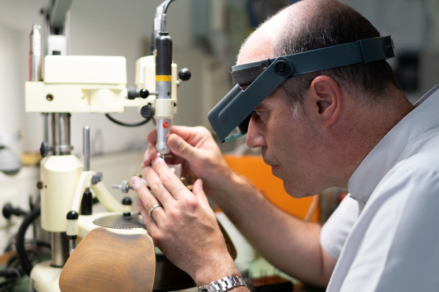 Zahntechniker mit Kopflupe bei der Präzisionsarbeit am Parallelometer